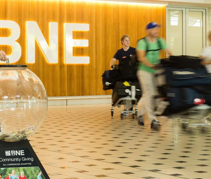 Passenger donating money to a Charity Giving Globe at the International Terminal