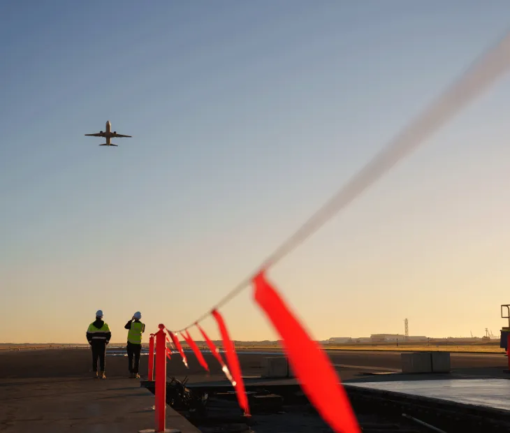 Plane flying over workers on the Legacy Runway