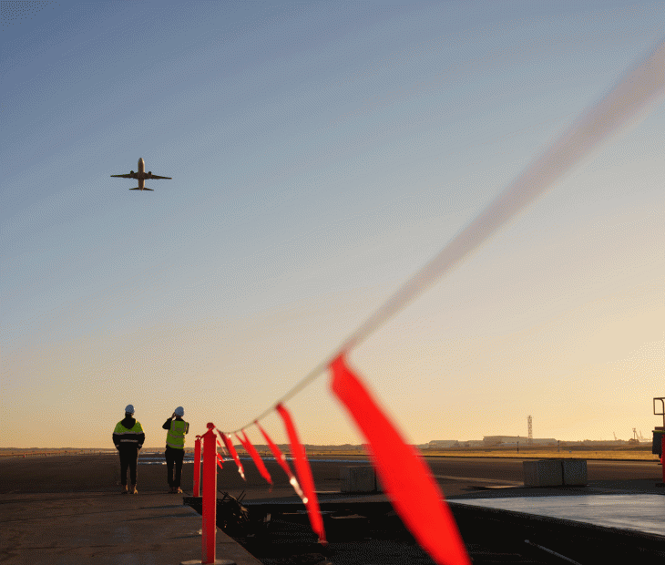 Plane flying over workers on the Legacy Runway