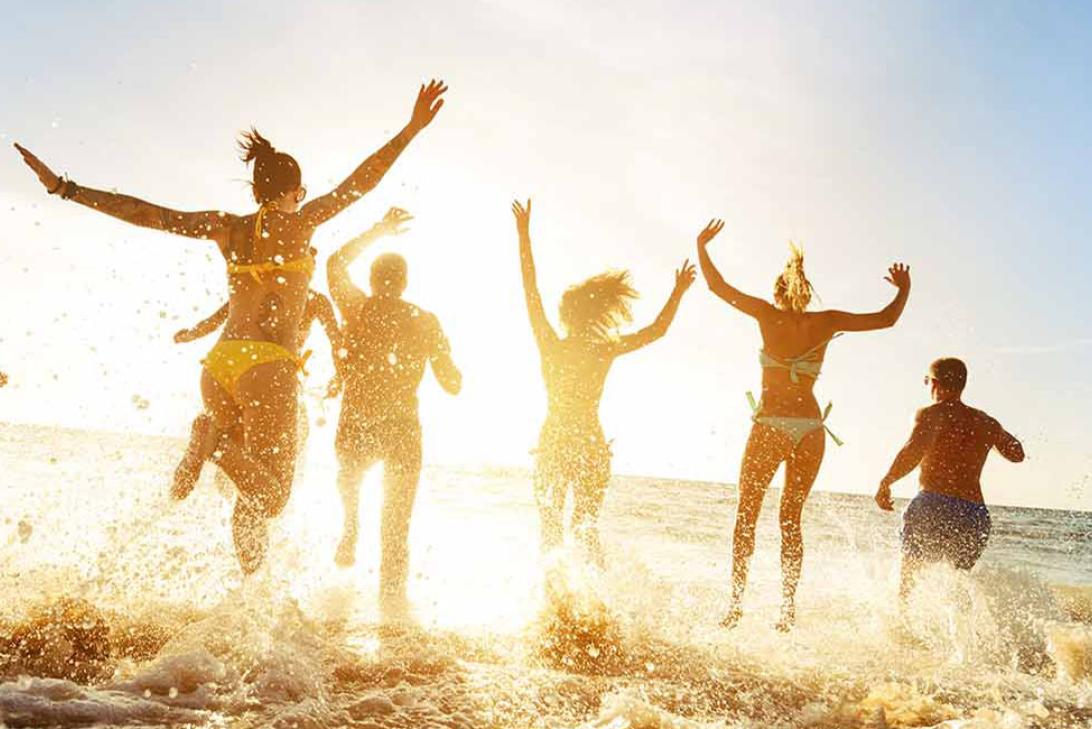 Group of friends running into the ocean | Top tips for travelling in a large group while keeping friendships intact