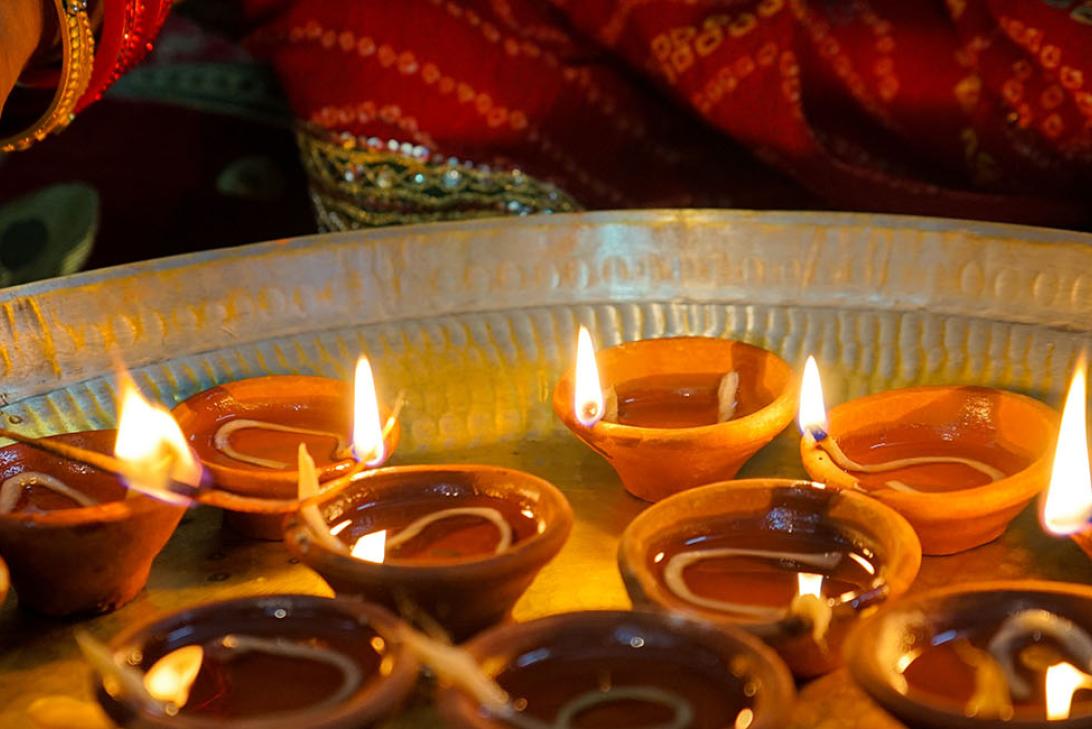 A hand lighting Diwali candles in small clay pots 