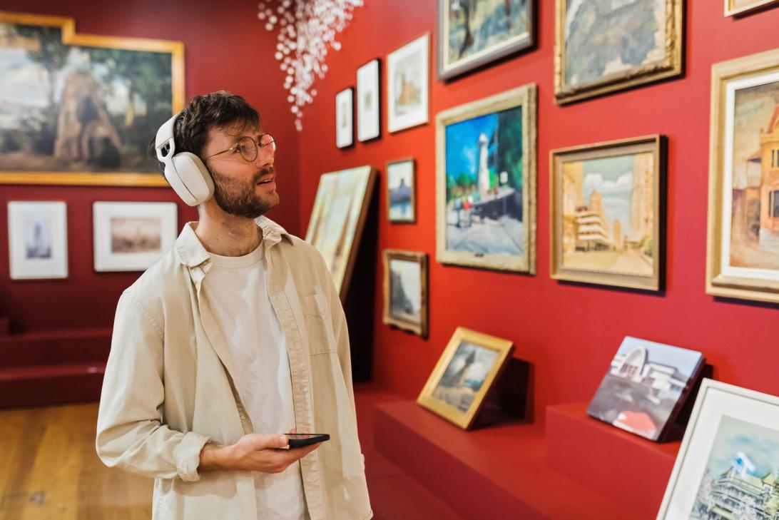 A man wearing headphones looking at artwork