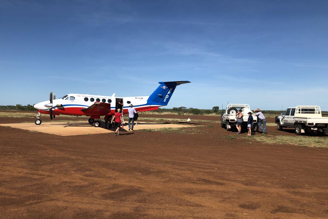 RFDS plane picking up a patient on a red dirt runway with two cars nearby